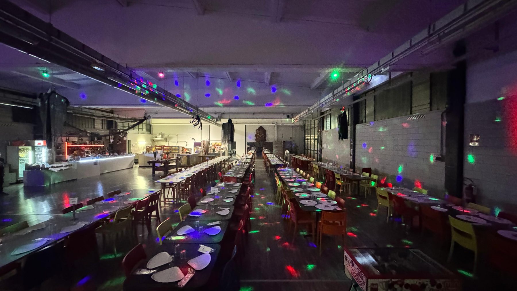 Le lunghe tavolate della sala giropizza di Pito Pitù a Cabiate, apparecchiate per la serata con luci colorate